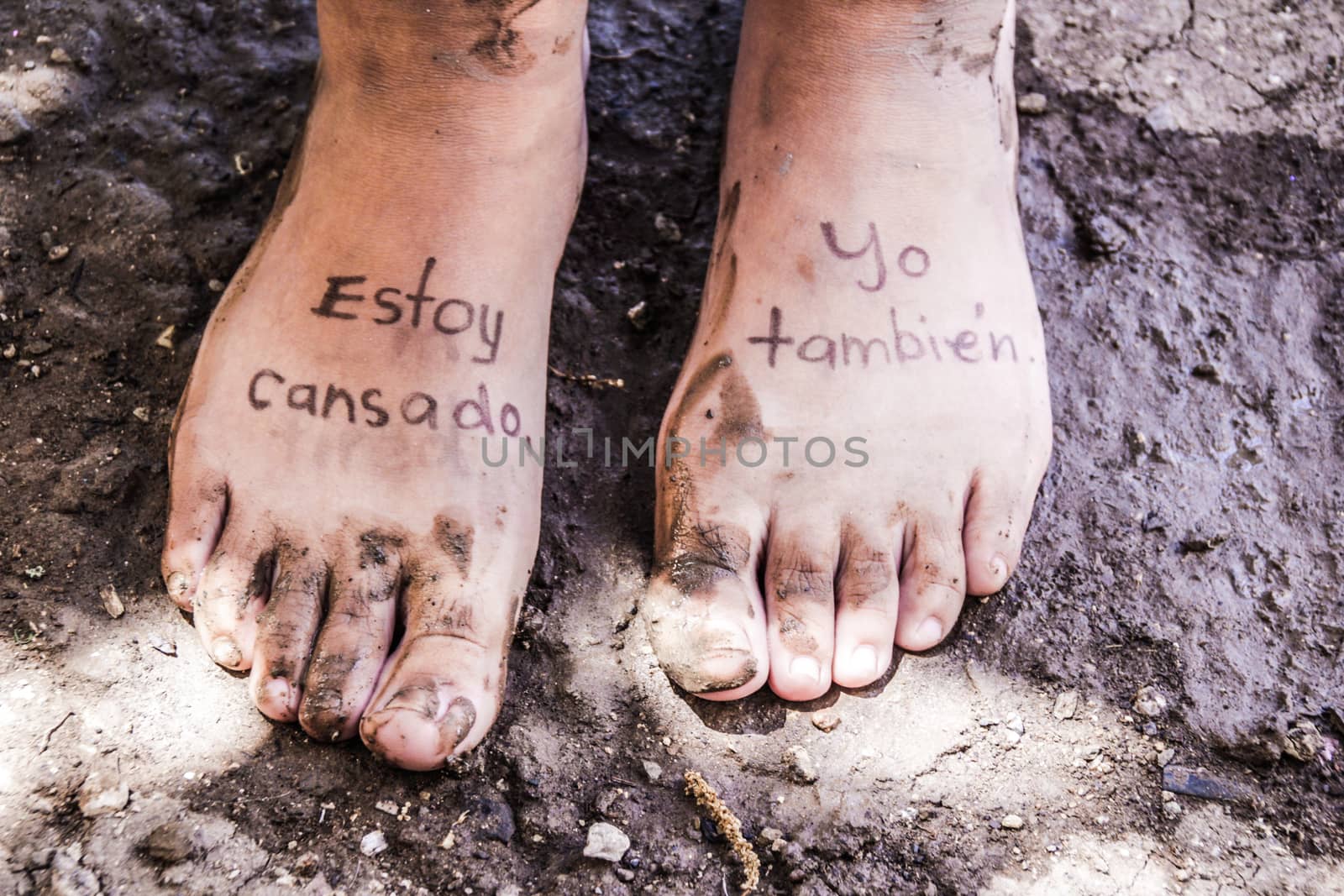 Photograph of a pair of human feet and the phrase in spanish: Estoy cansado, yo tambien, which means: Im tired, me too
