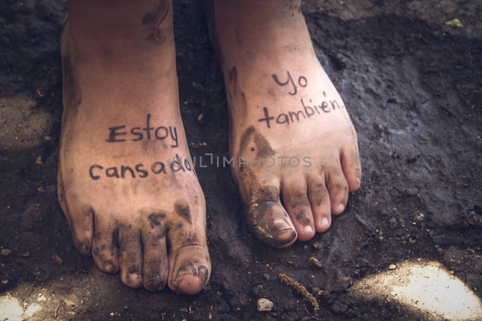 Photograph of a pair of human feet and the phrase in spanish: Estoy cansado, yo tambien, which means: Im tired, me too