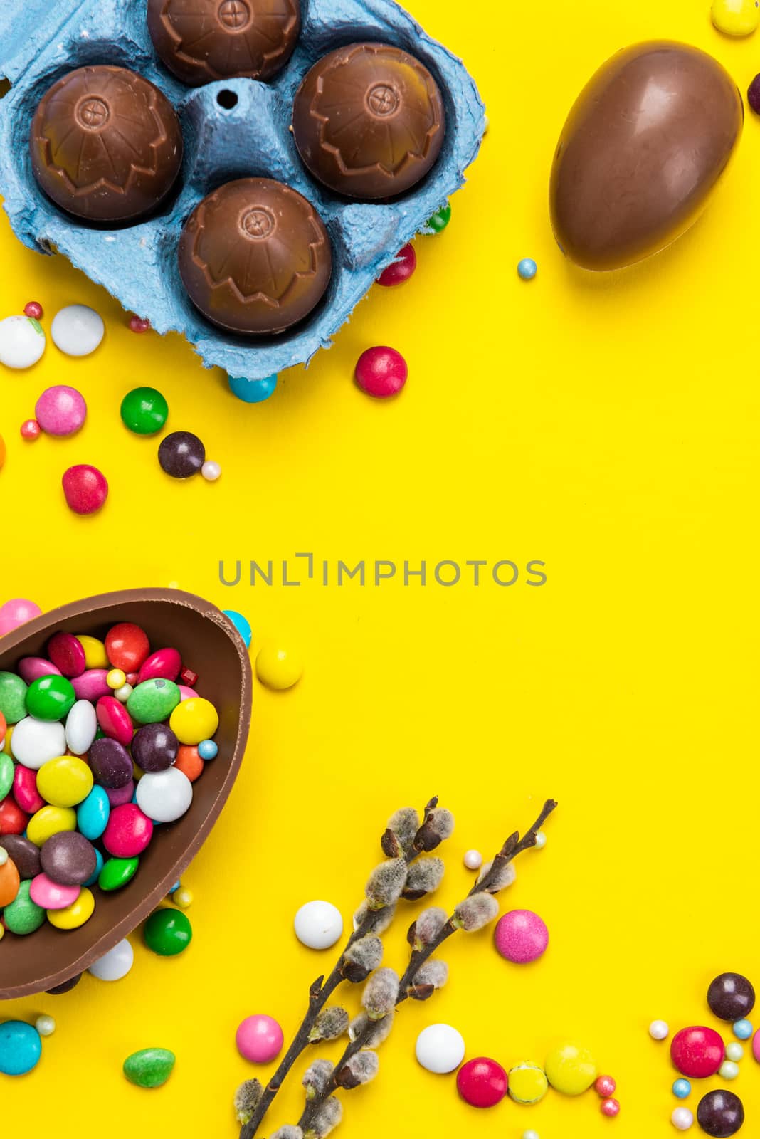 Colorful Easter BAckground. Chocolate Eggs and Candy on Yellow Background. Copy Space on Flat Lay Design.