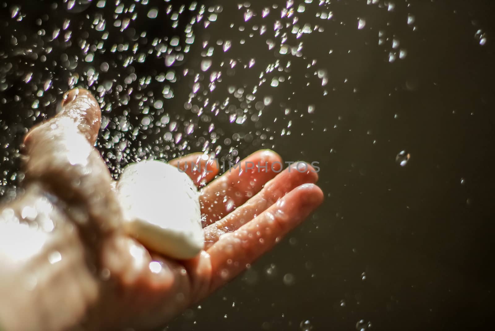 Photograph of an open human hand with soap under water drops