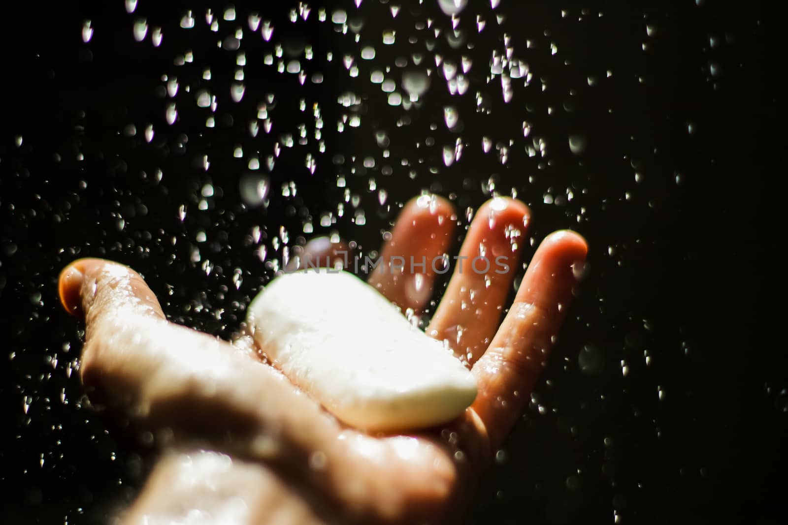 Photograph of an open human hand with soap under water drops