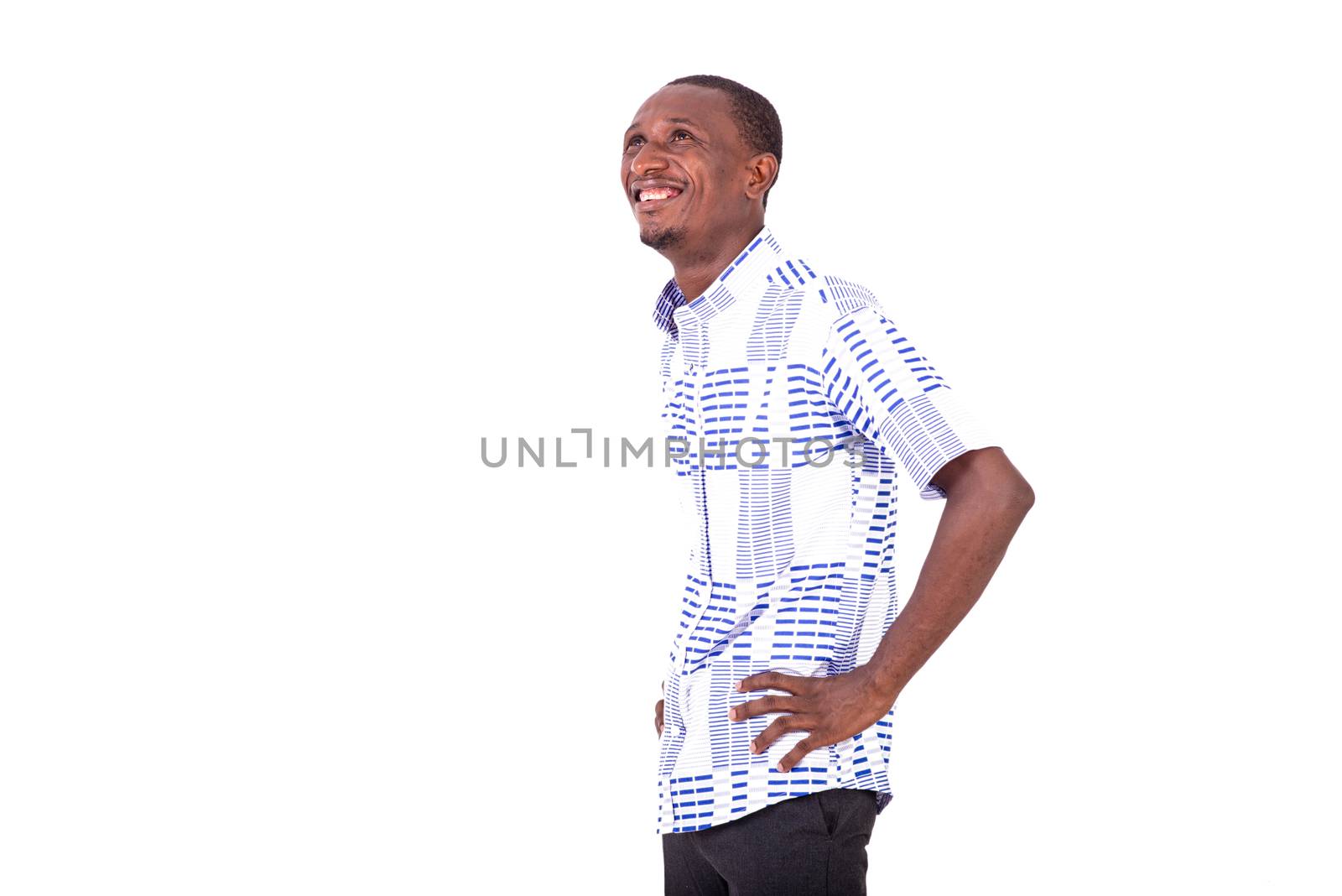young happy man standing sideways keeping hands on his hips and looking upwards smiling.