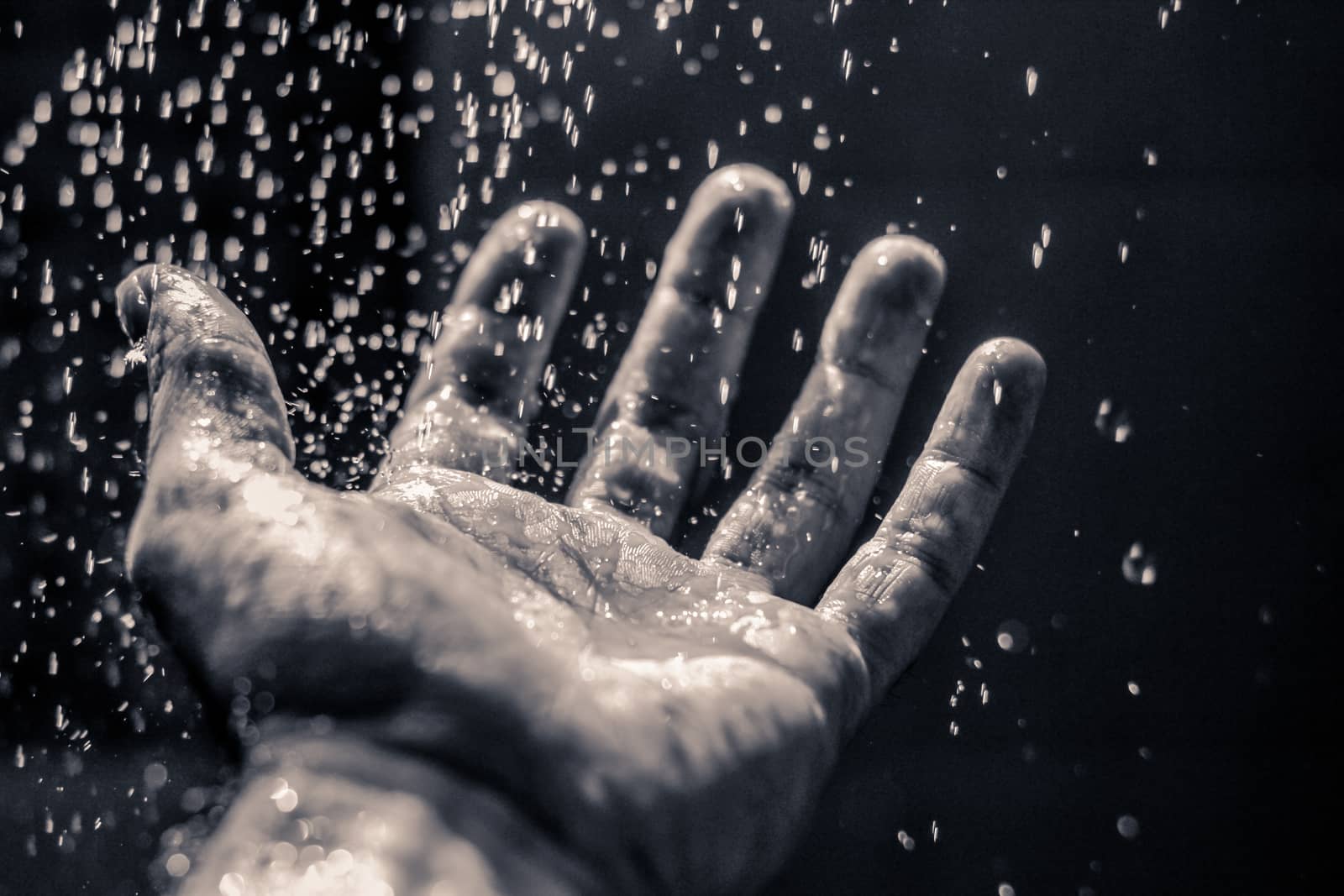 Photograph of an open human hand under water drops