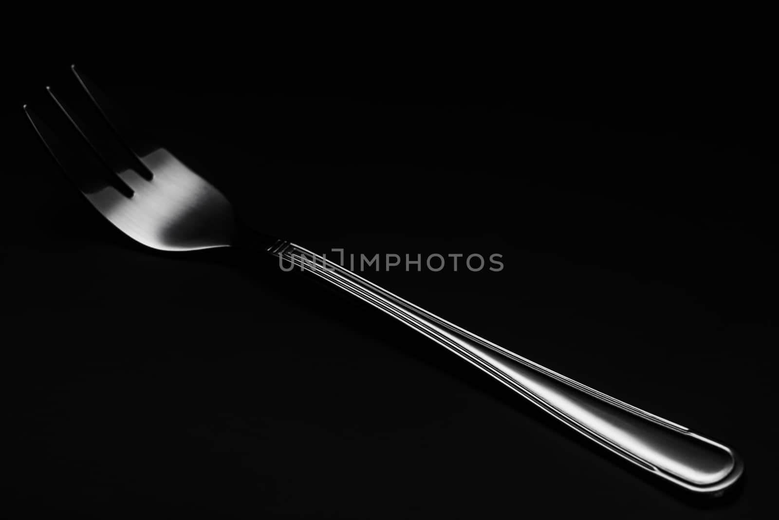 One Silver or Stainless Steel Fork. Close Up Detail view. Dark Background. Low Key Image.