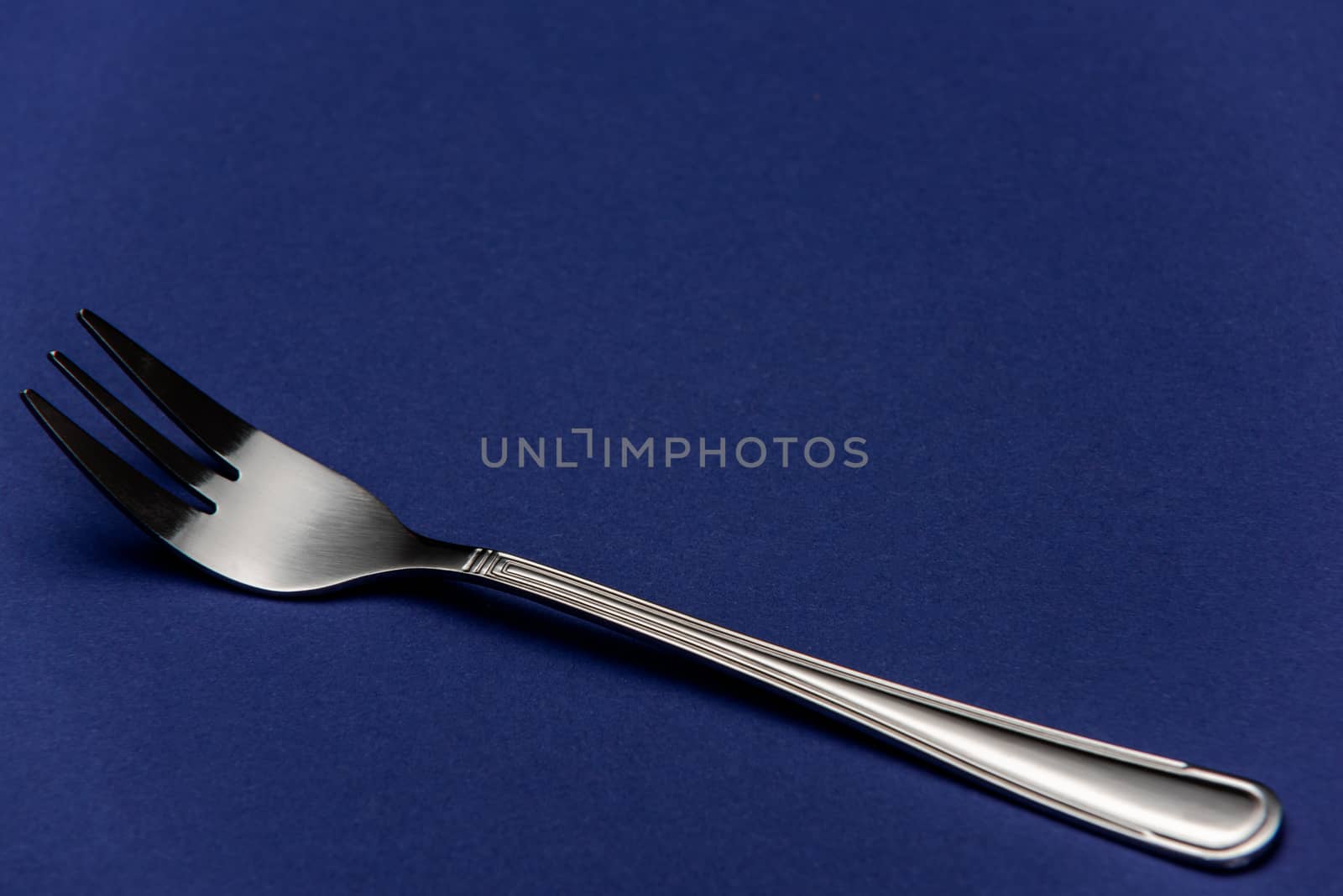 Single One Stainless Steel Fork on Blue Background. Detail Close by merc67