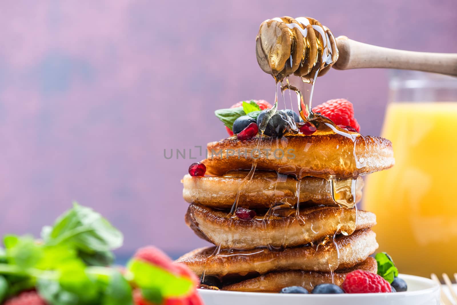 Pouring Honey on Pancakes Stack Topped with fresh Fruits. Shrove by merc67