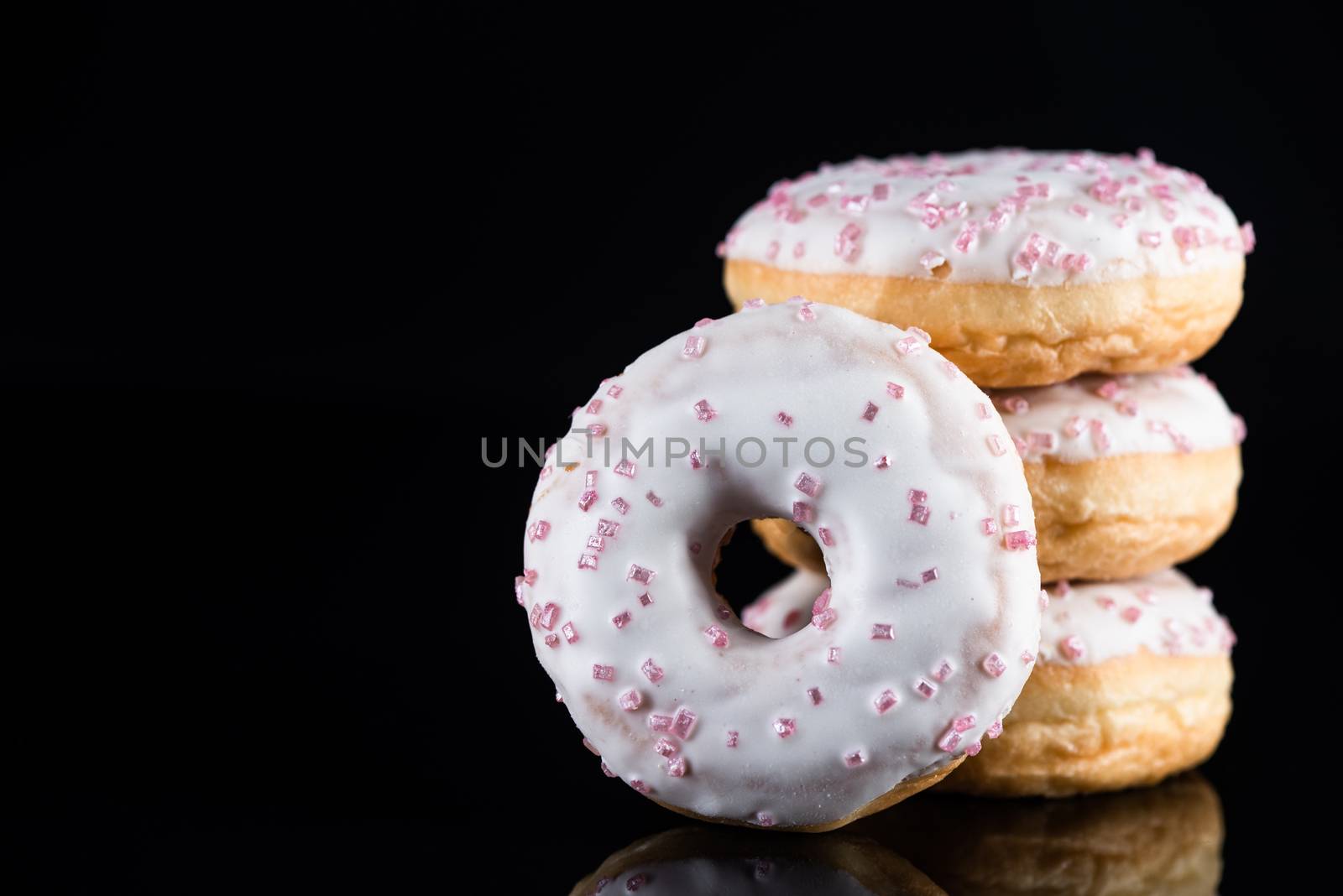 Stack of  White Chocolate Donuts or Doughnuts on Black Background with Copy Space.