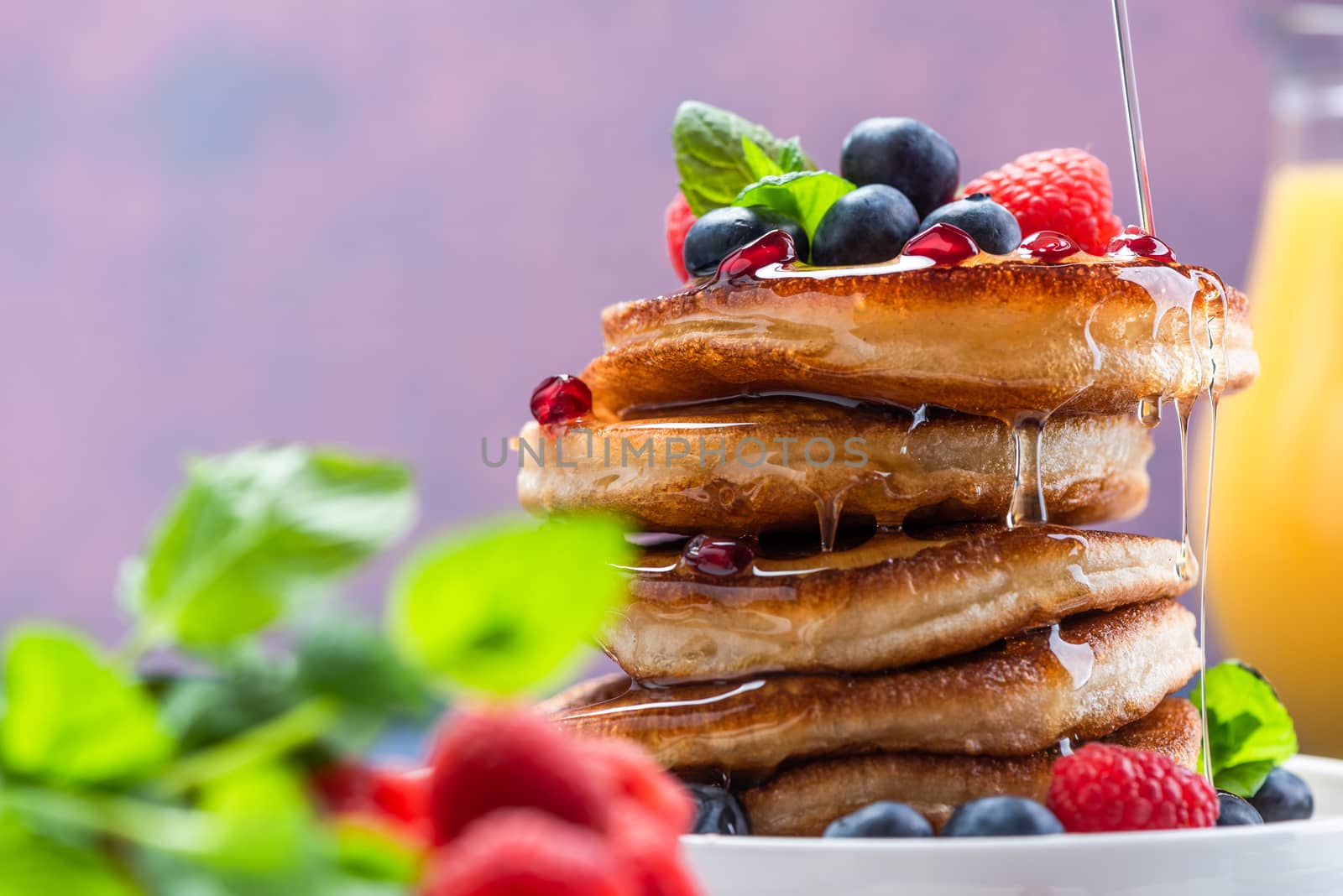 Pouring Maple Syrup on American Pancakes Topped with Fresh Fruits. Shrove Tuesday.