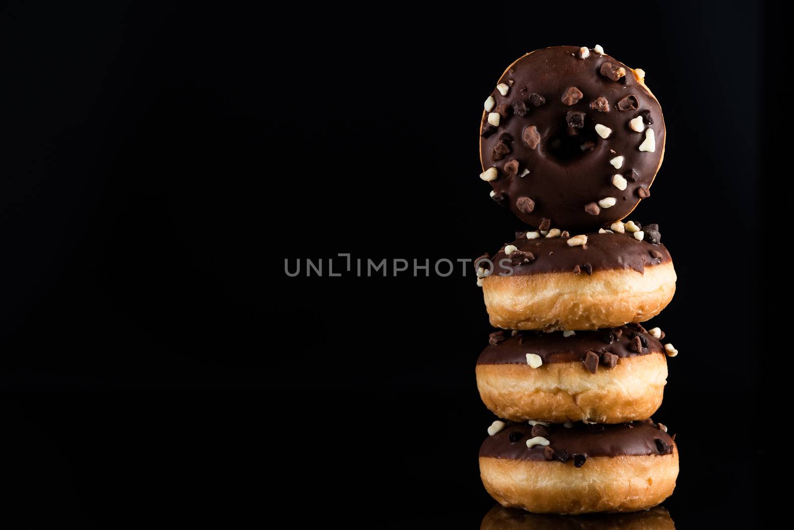 Chocolate Donuts or Doughnuts Tower on Dark Background. Copy Space for Text.