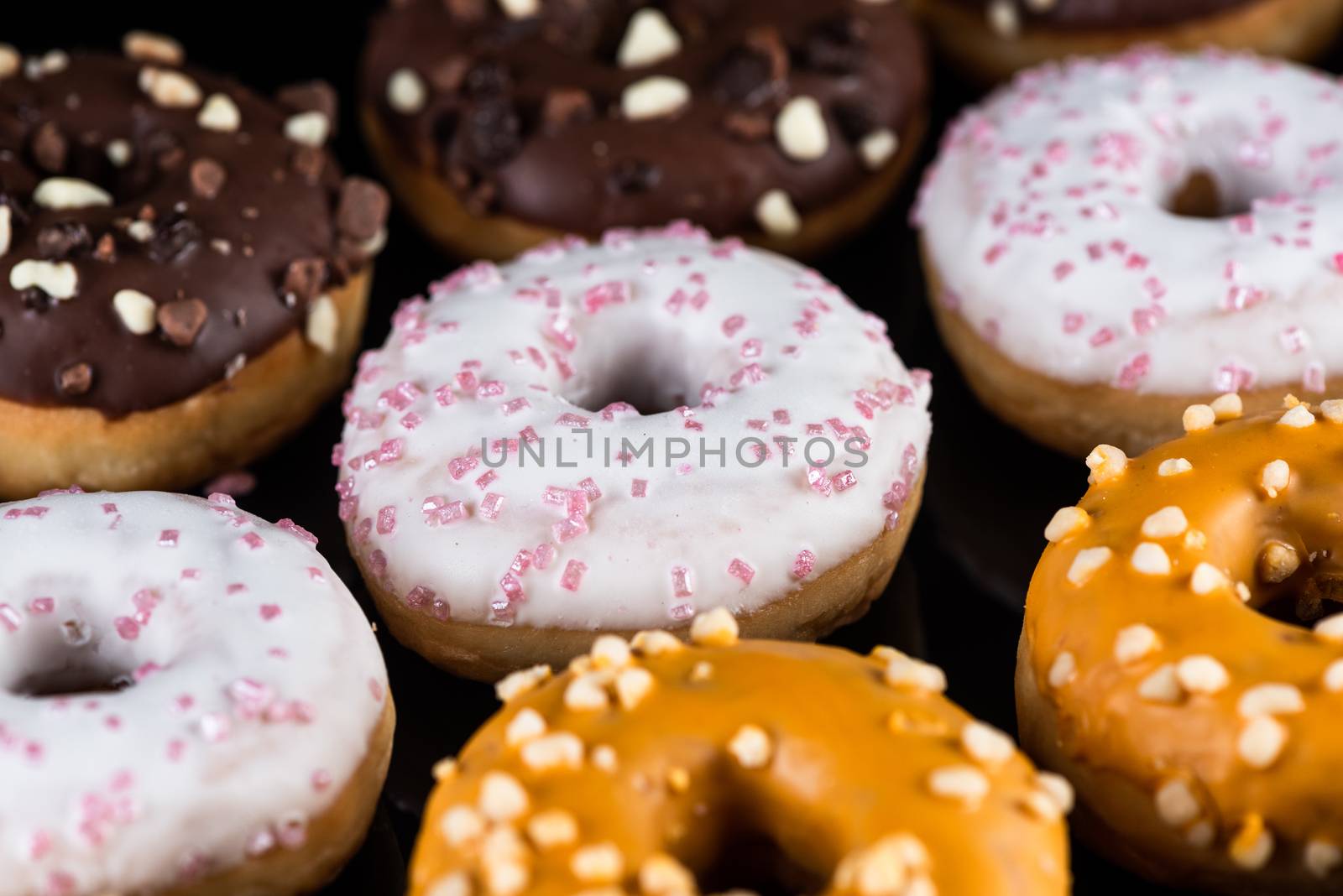Decorated Donuts or Doughnuts Flat Lay on Dark Background.
