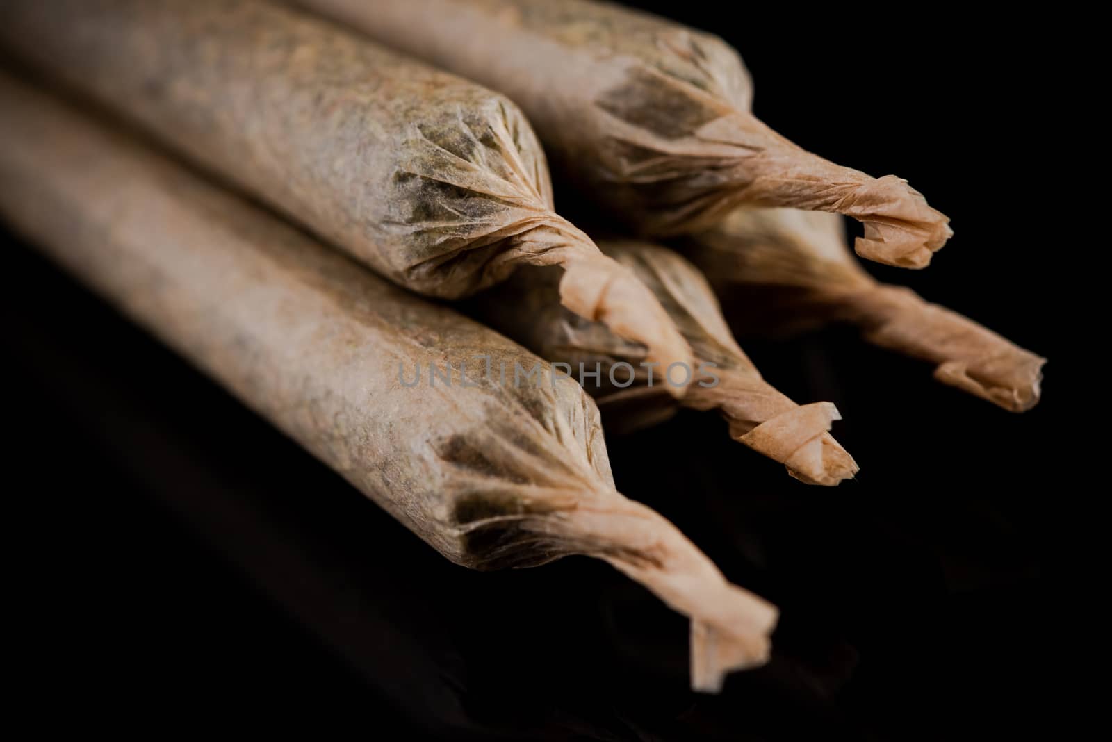 Cannabis Marijuana Rolled in Joints on Dark Reflective Background.
