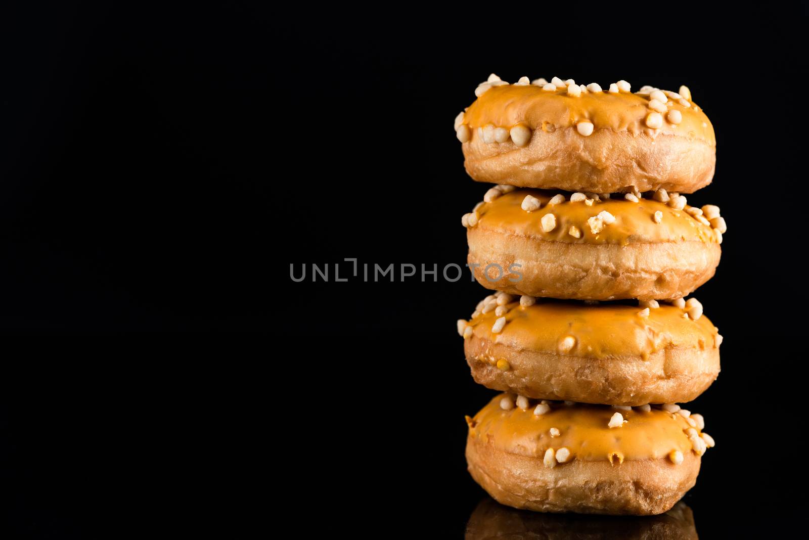 Stack of  Salted Caramel Donuts or Doughnuts on Black Background with Copy Space.