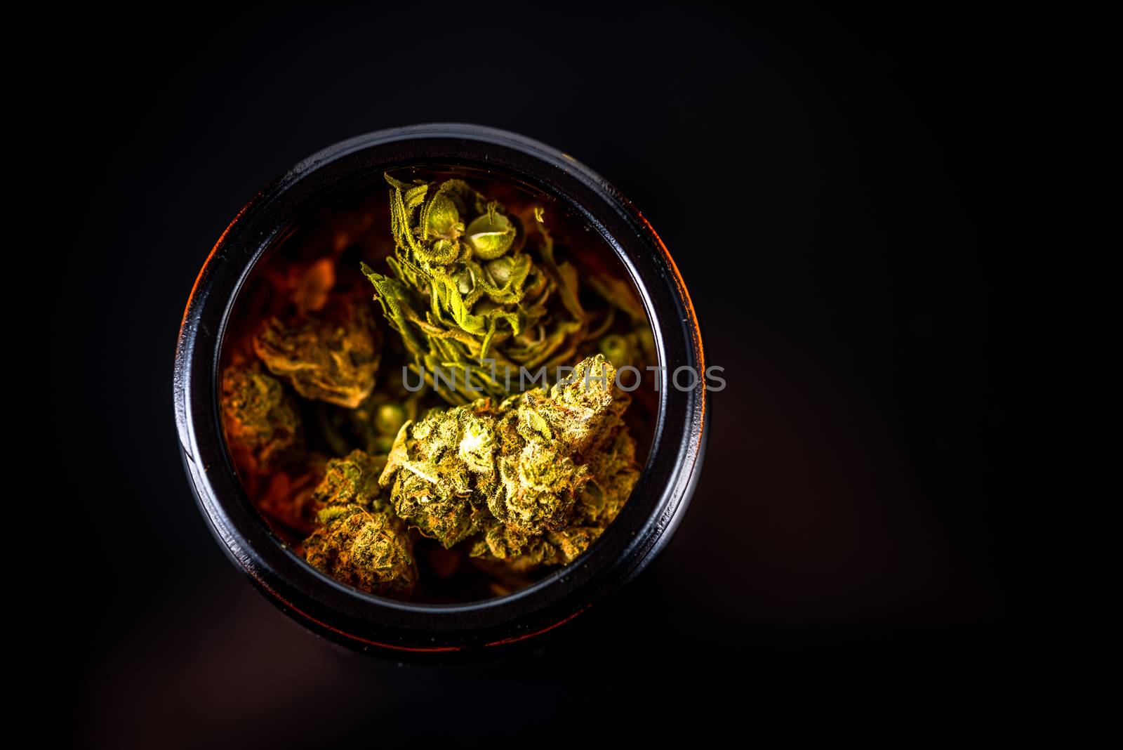 Cannabis Flower Buds in Glass Jar, Top Down Close Up. Dark Background. Medical Marijuana Concept.