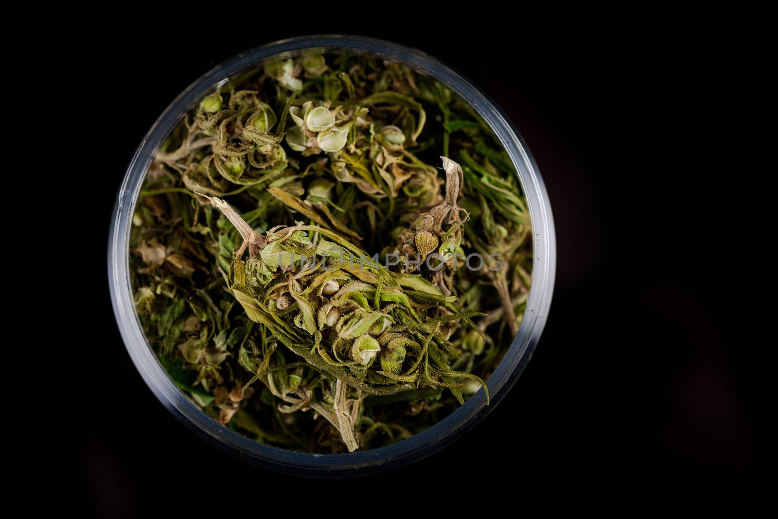 Cannabis Flower Buds in Glass Jar, Top Down Close Up. Dark Background. Medical Marijuana Concept.