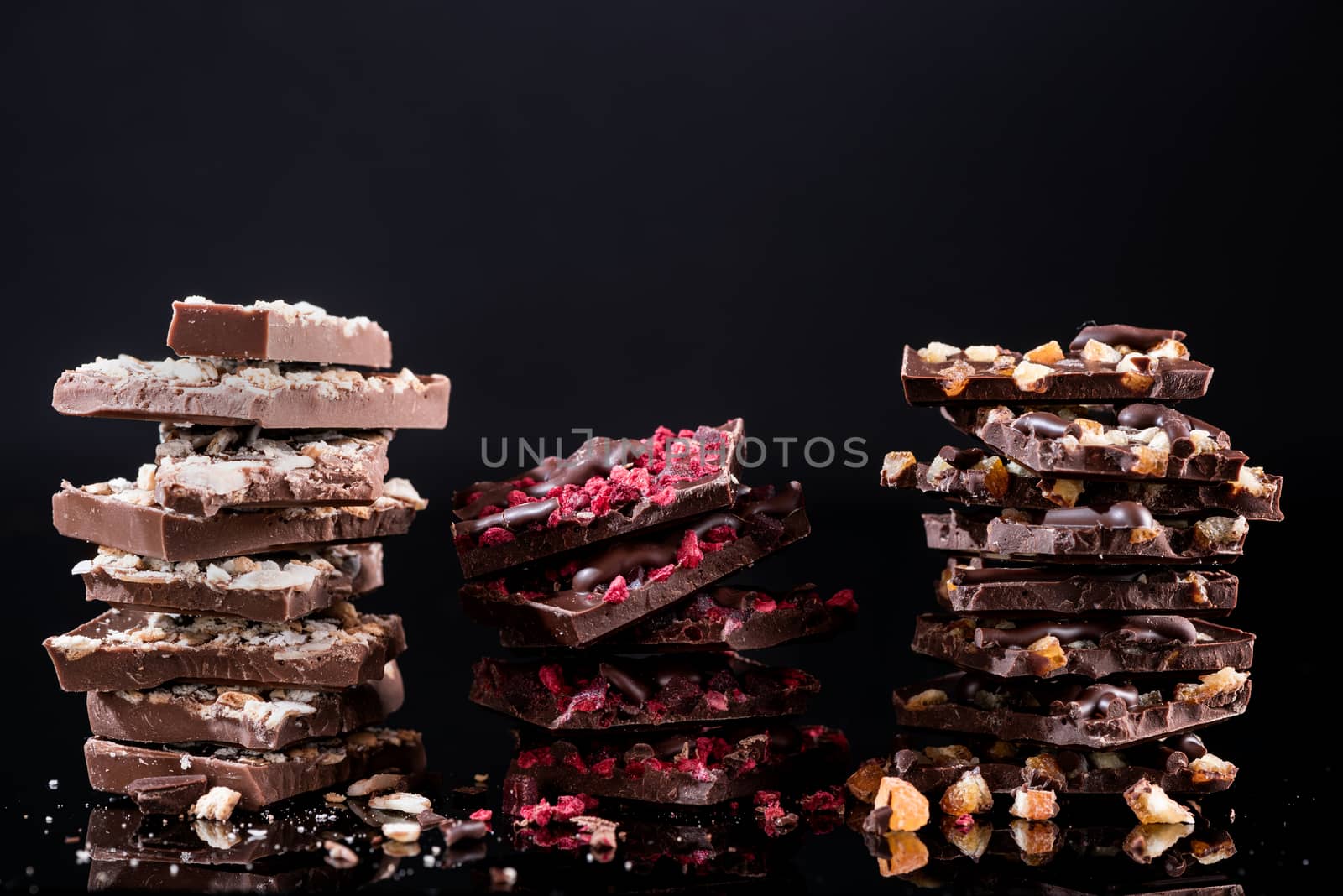 Stack of Broken Chocolate Pieces on Black Background. Copy Space. Closeup View.
