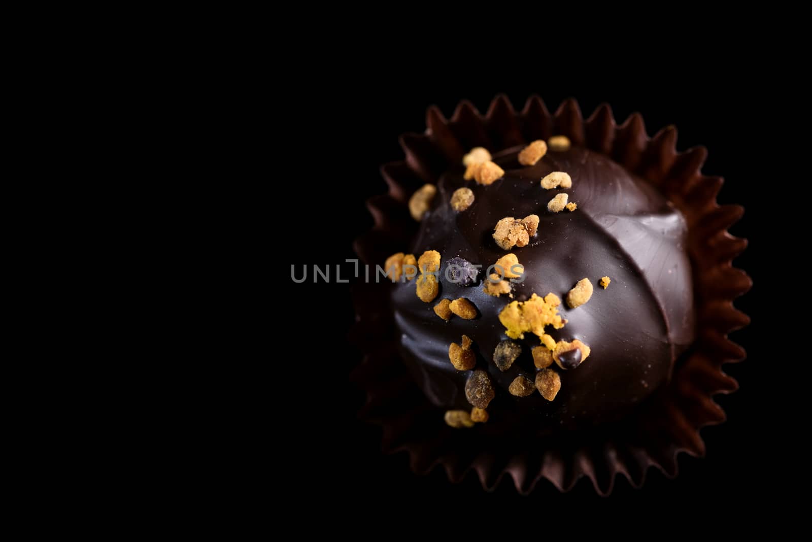 One Single Handmade Chocolate Praline Close Up View. Dark Background with Copy Space.