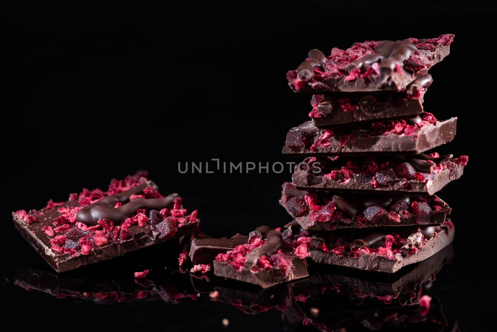 Stack of Broken Chocolate Pieces on Black Background. Copy Space. Closeup View.