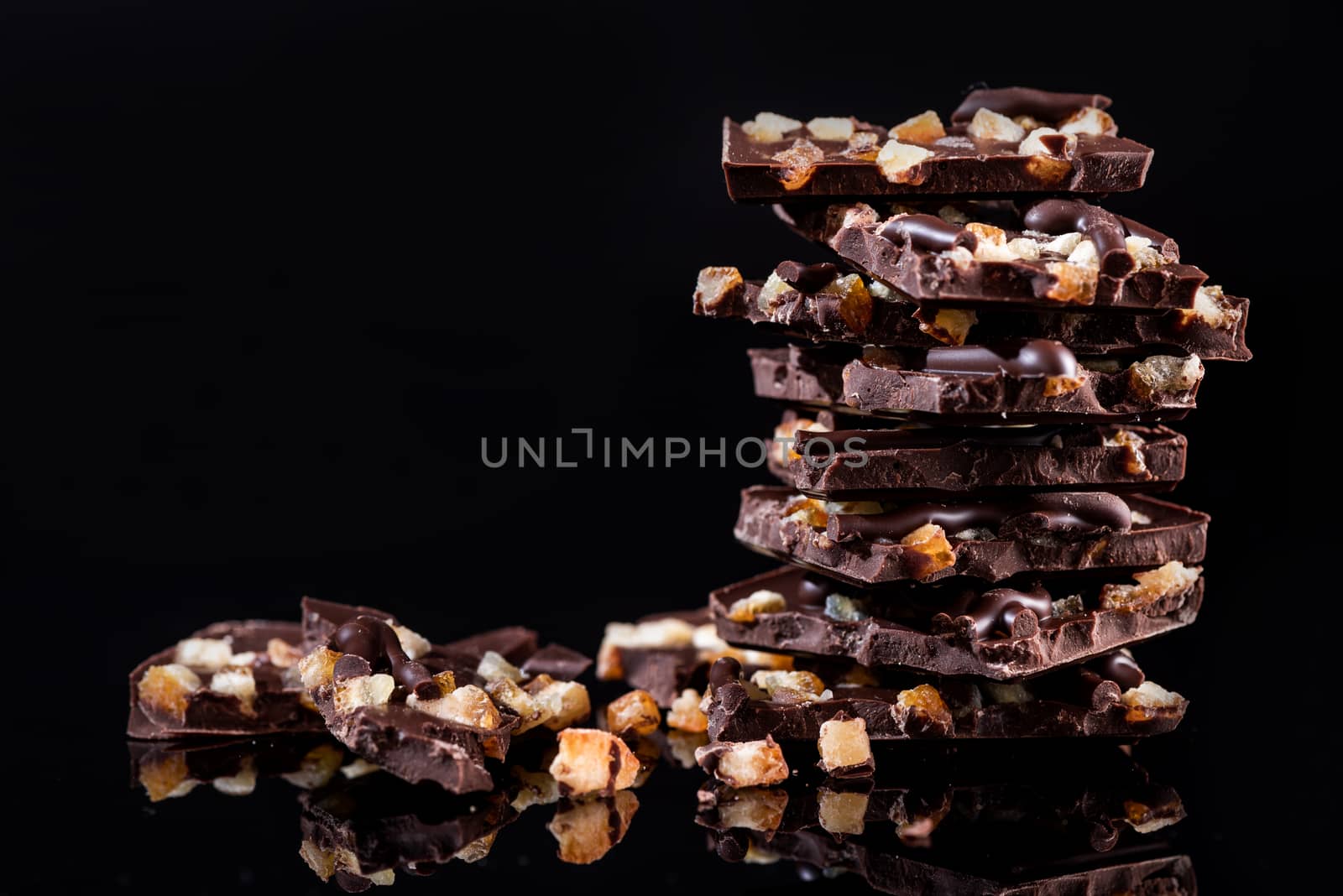 Stack of Broken Chocolate Pieces on Black Background. Copy Space. Closeup View.