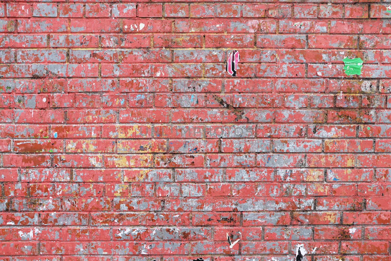 Red brick with remnants of pasted posters. Wall texture