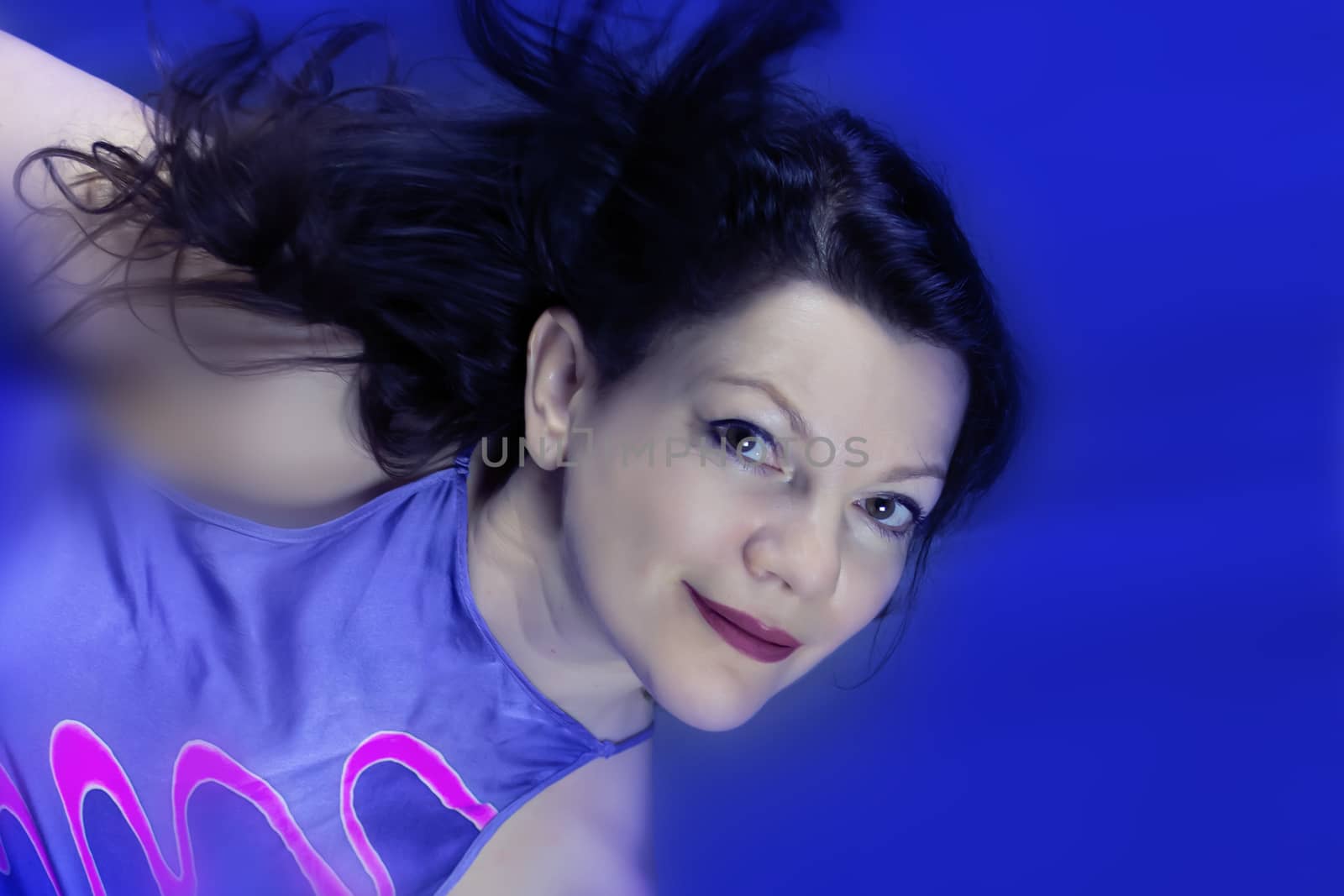 Portrait of a beautiful fashionable middle-aged woman with long dark hair, posing on a dark blue background. The concept of preserving youth at any age.