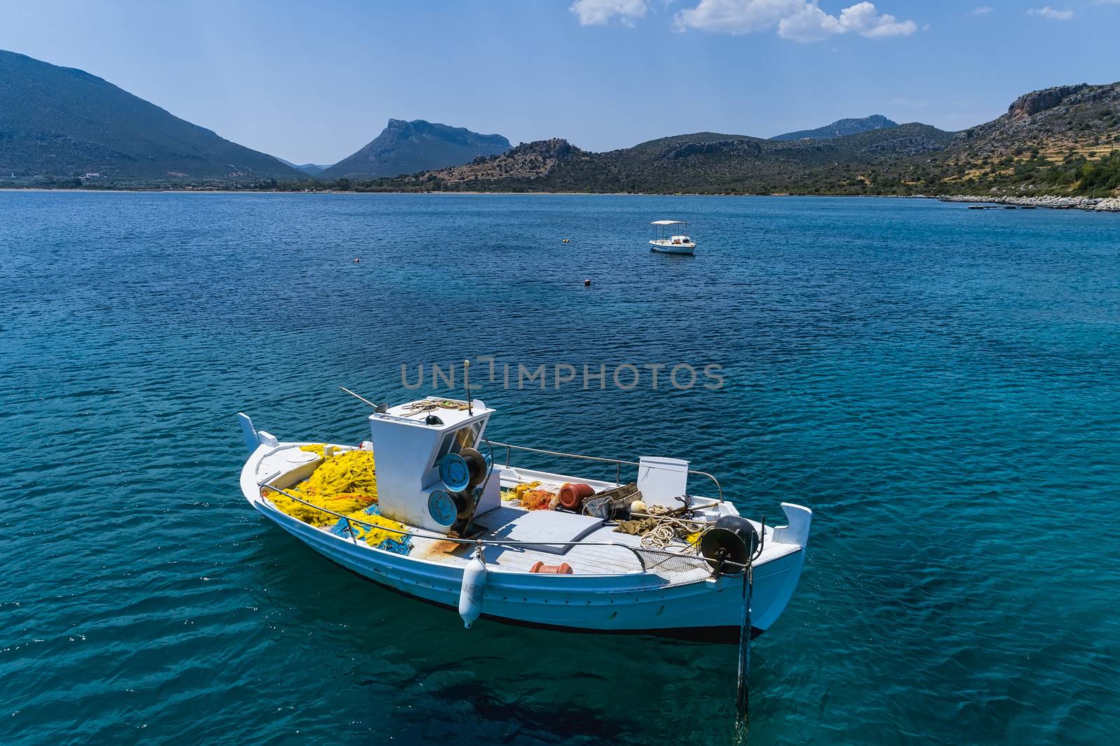 Aerial photo top view of small traditional fishing boat in tropical emerald and turquoise clear sea. Peloponnese, Greece