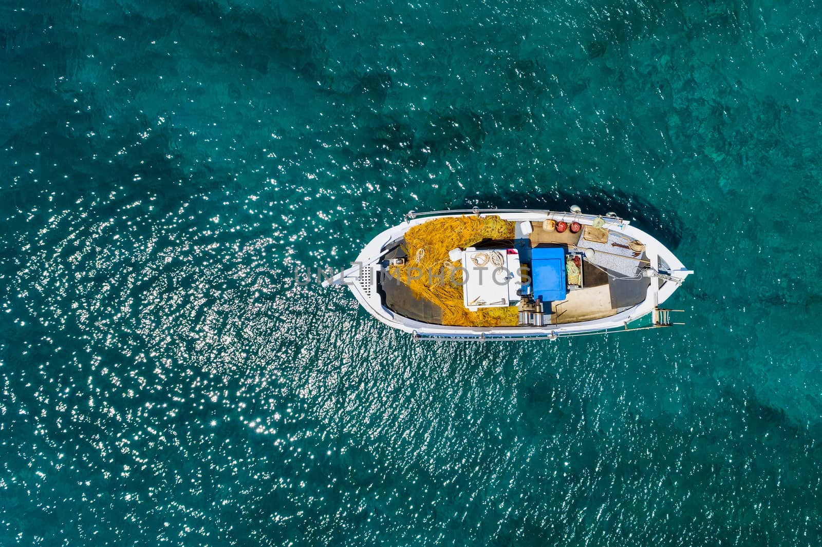 Aerial photo top view of small traditional fishing boat in tropical emerald and turquoise clear sea. Peloponnese, Greece
