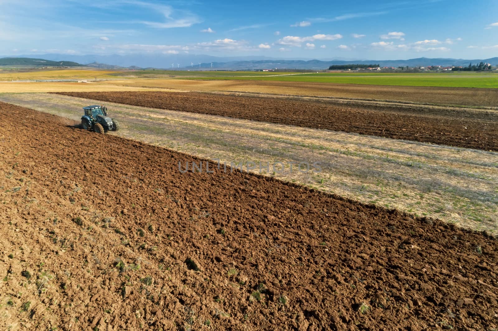 aerial view of the tractor plows in the field, by ververidis