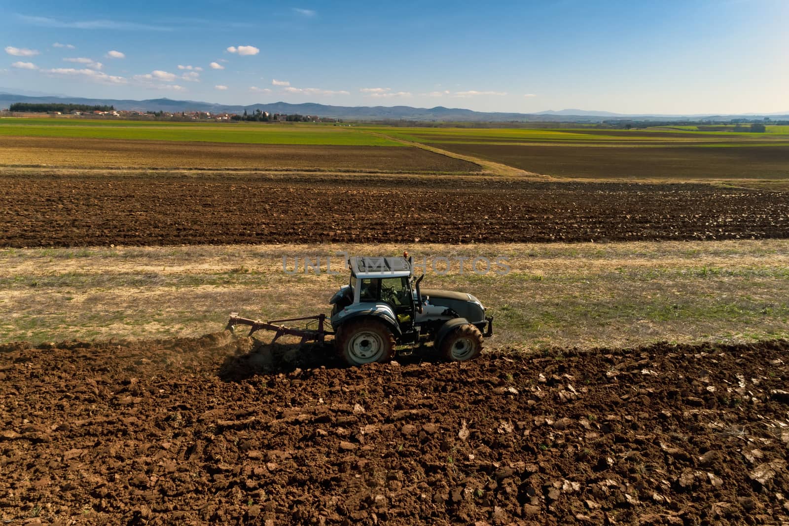 aerial view of the tractor plows in the field, by ververidis