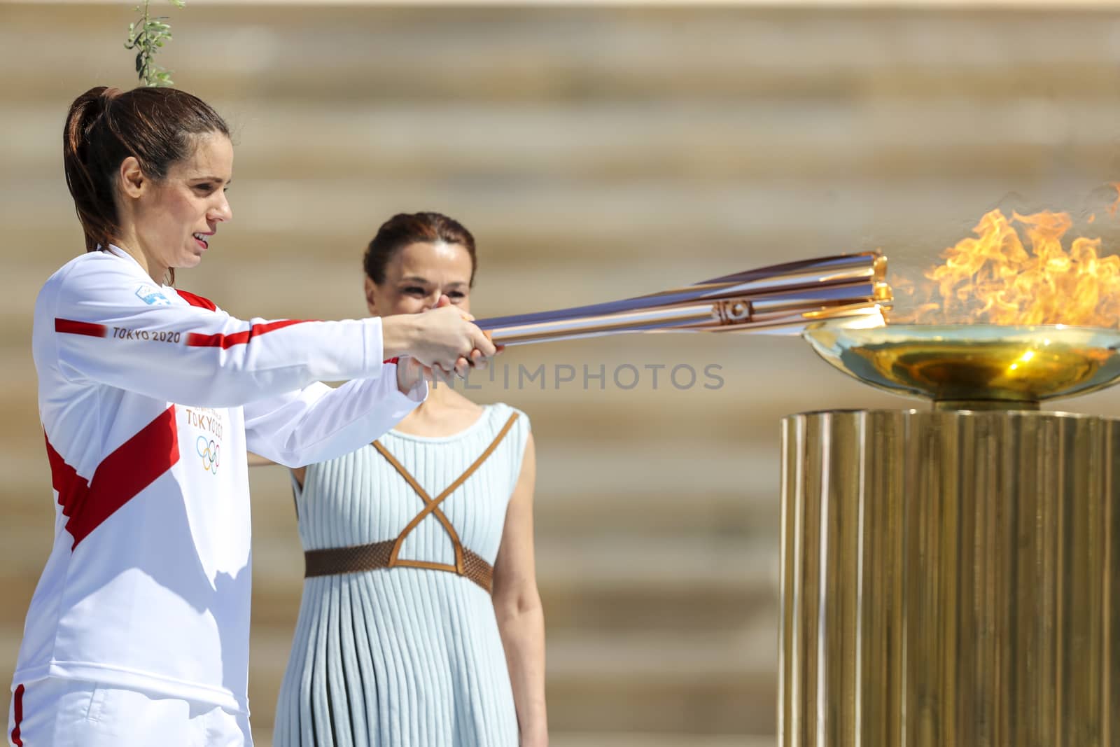 Athens, Greece - March 19, 2020: Olympic Flame handover ceremony for the Tokyo 2020 Summer Olympic Games at the Panathenaic  Stadium. Greek athlet K. Stefanidi (L) is seen lighting the cauldron