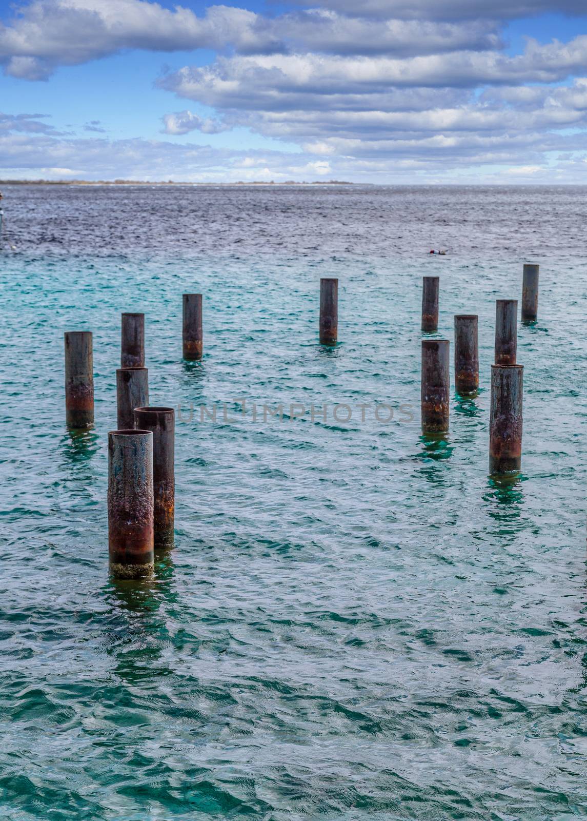 Rusty Metal Pilings in blue water of Harbor