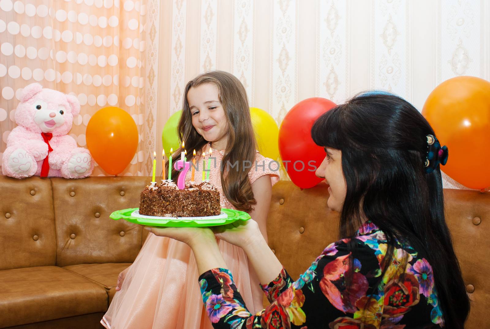 mom gives daughter in a pink dress birthday cake