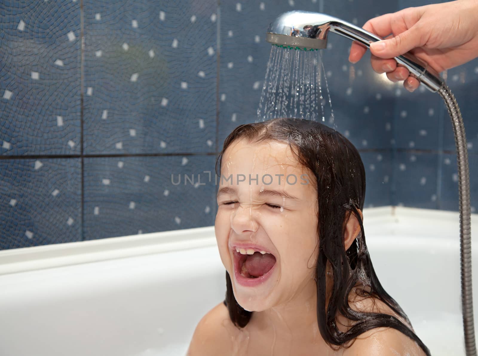 mothers's hand pours a little girl out of the shower in the bathroom