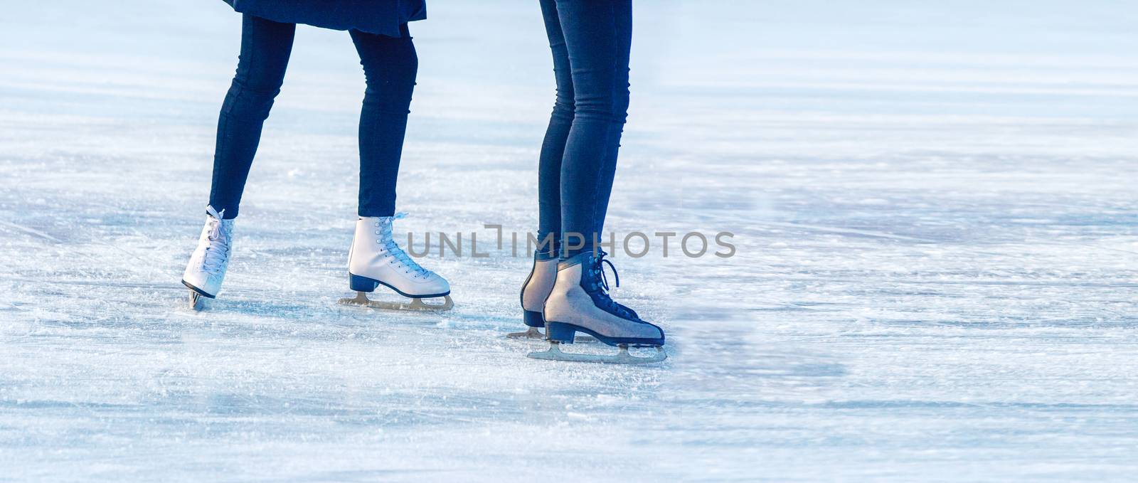 two young girls are skating on the rink. feet closeup