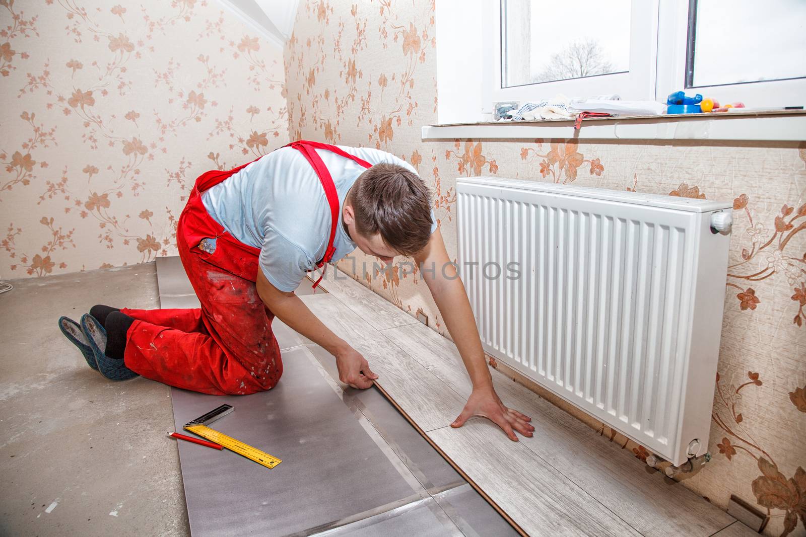 young handyman installing wooden floor in new house