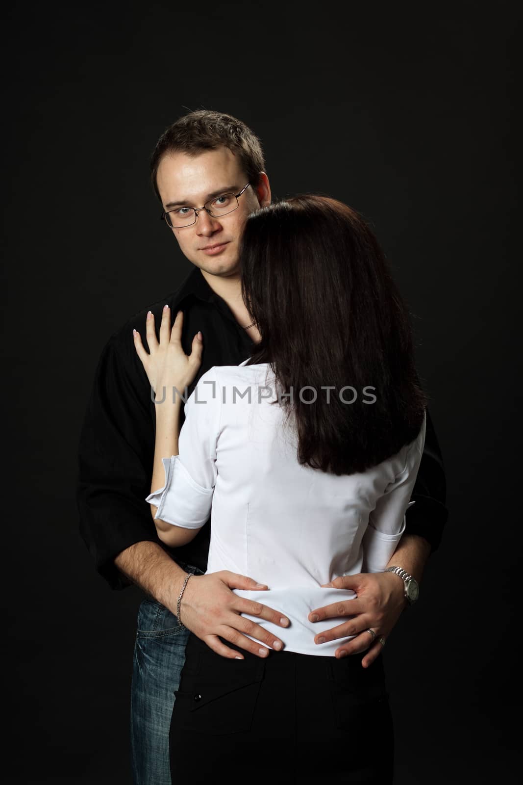 young beautiful couple posing standing in studio on black background