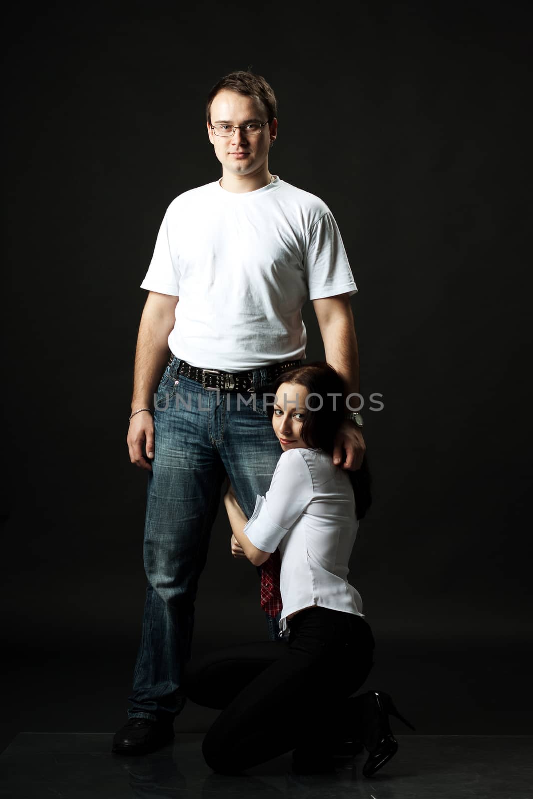 young family posing standing in studio on black background