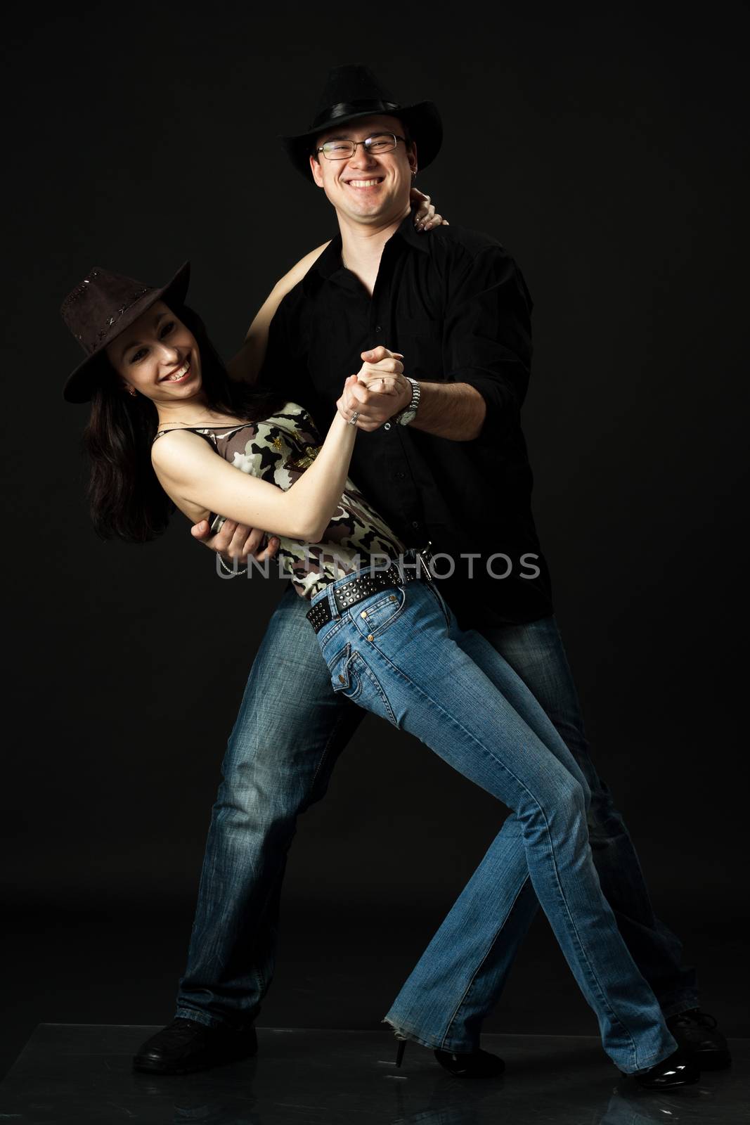 handsome young couple dancing in studio on black background