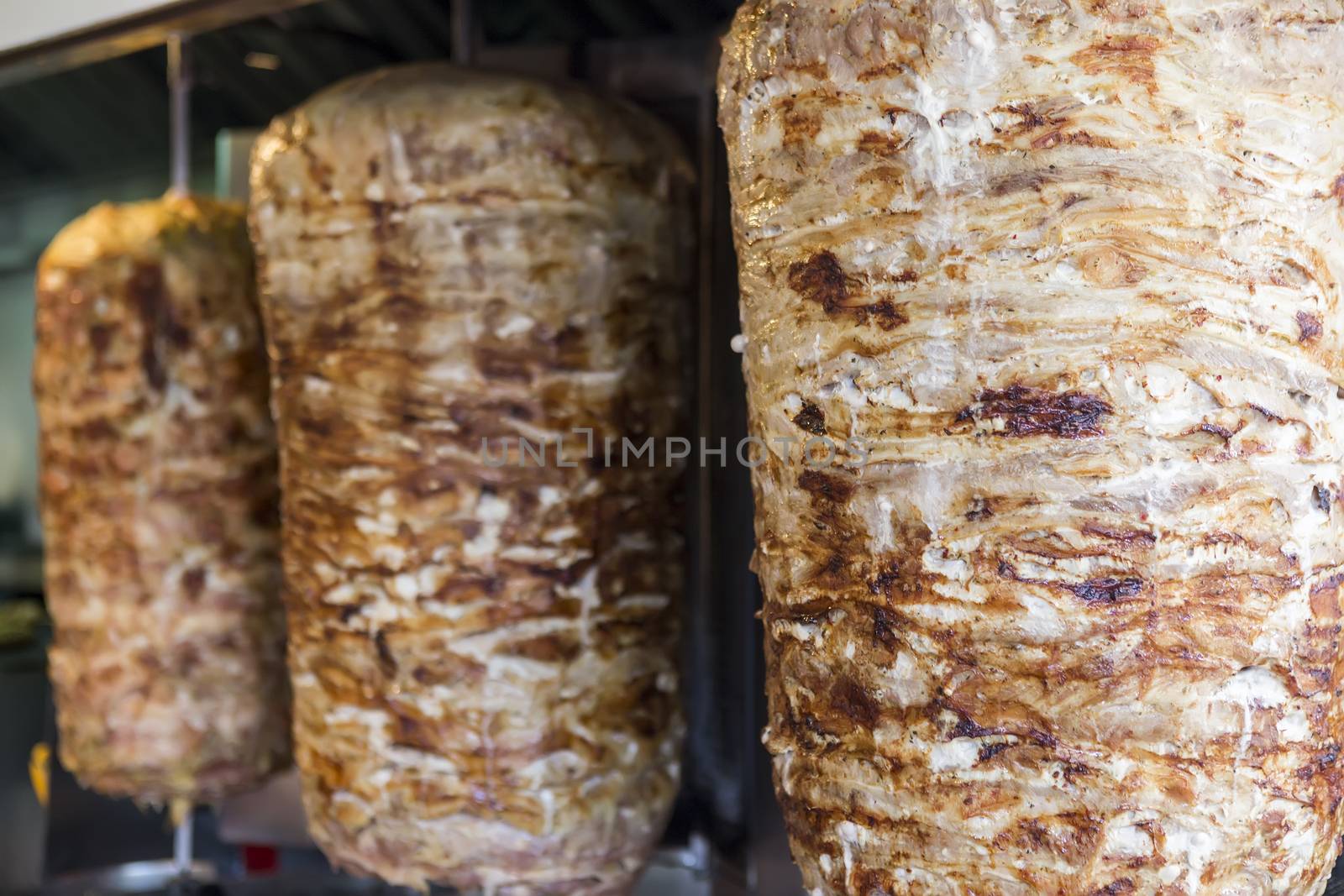 A pair of rotating skewered chicken and lamb meat grilled and ready to serve in a typical Middle Eastern sandwich