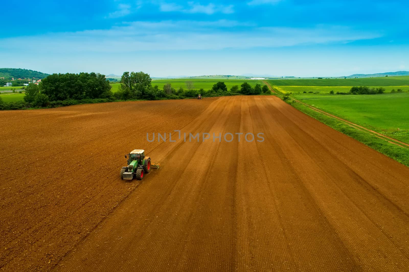 Aerial shot of  Farmer with a tractor on the agricultural field  by ververidis