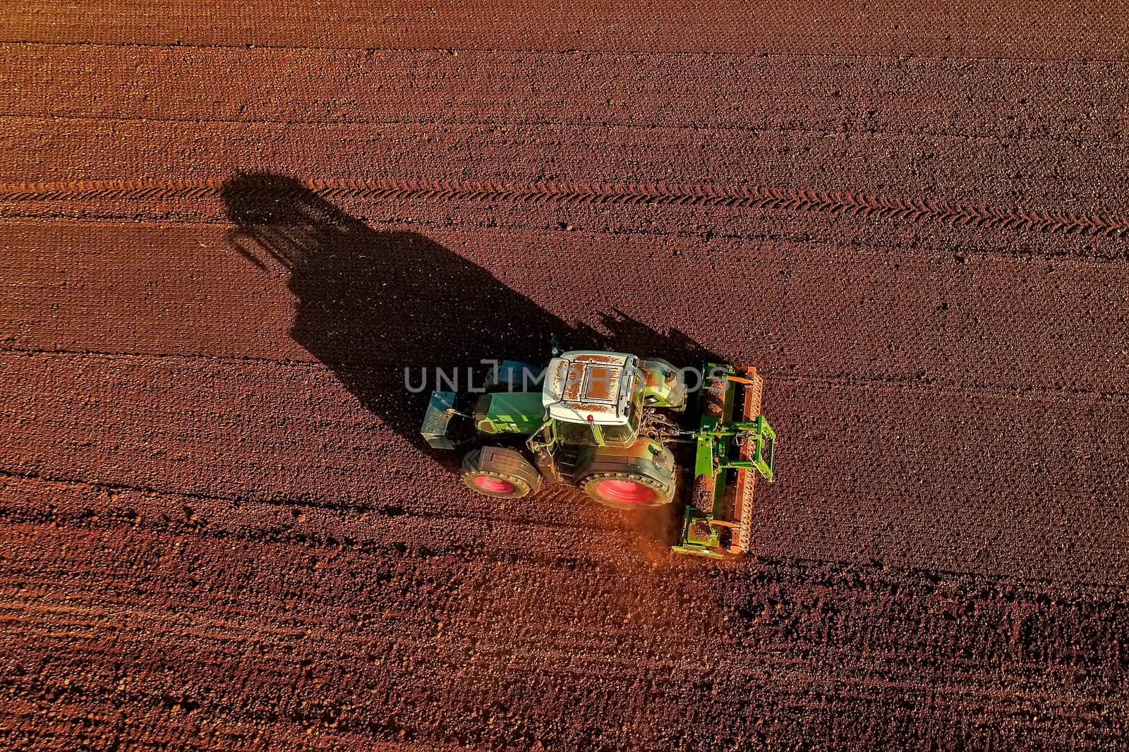 Aerial shot of  Farmer with a tractor on the agricultural field sowing. tractors working on the agricultural field in spring. Cotton seed