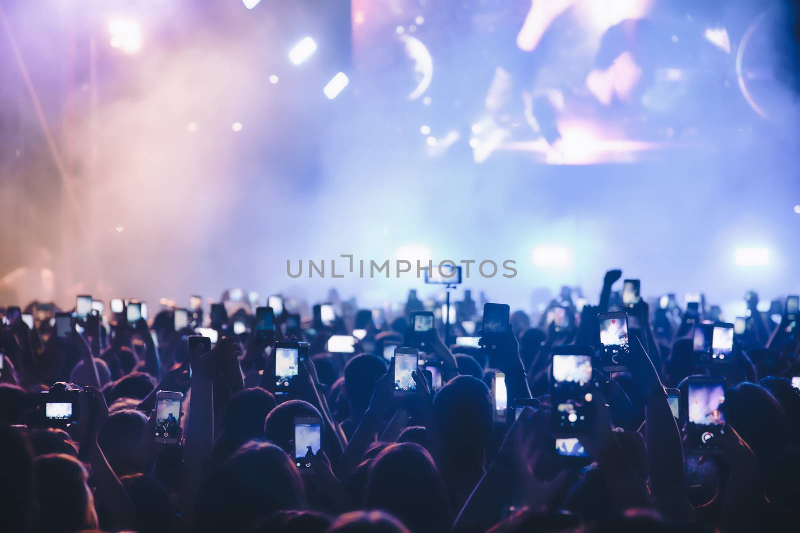 People taking photographs with smart phone during a public music concert