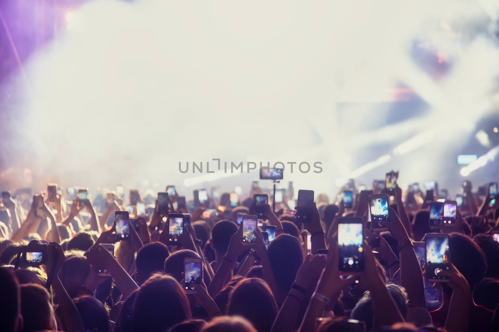 People taking photographs with smart phone during a public music concert