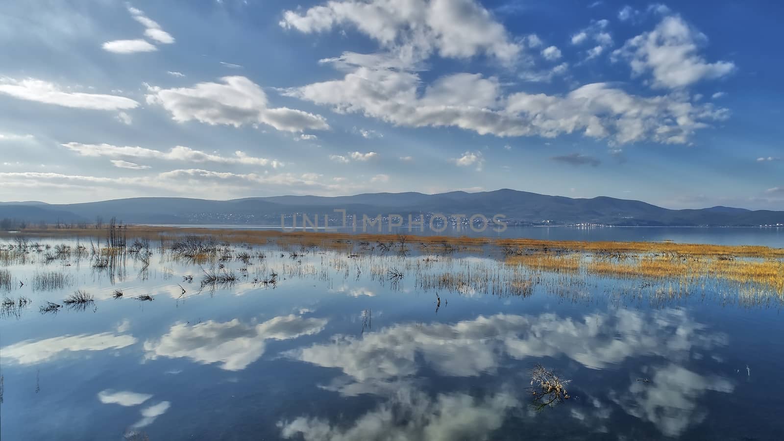 reflection of clouds at the wetland of Lake Doriani on a winter  by ververidis