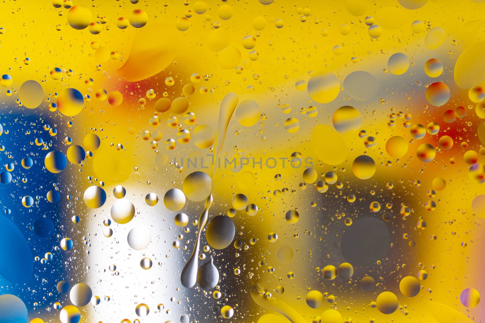The hue abstract composition with oil drops in water. Yellow, blue, white colors.