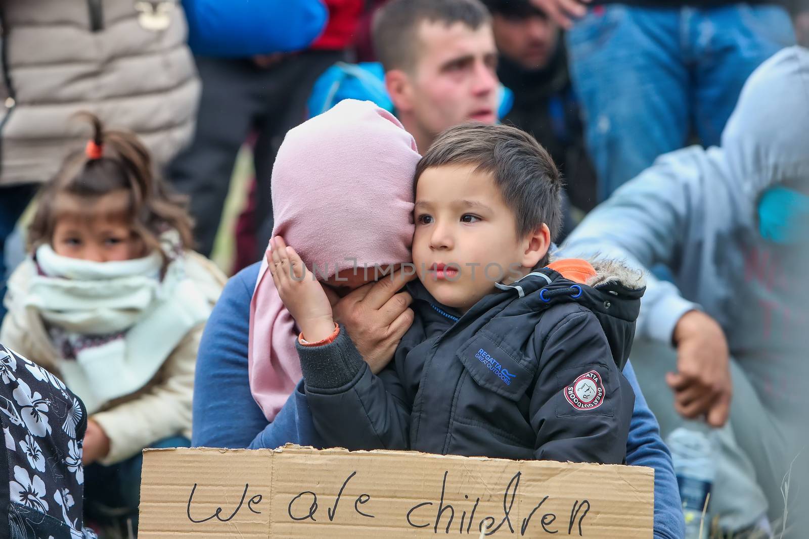 Thessaloniki, Greece - April 6, 2019: The little refugee gives courage to his mother. She just realized that has fallen victim to fake news and can’t continue their journey from Greece to Europe.