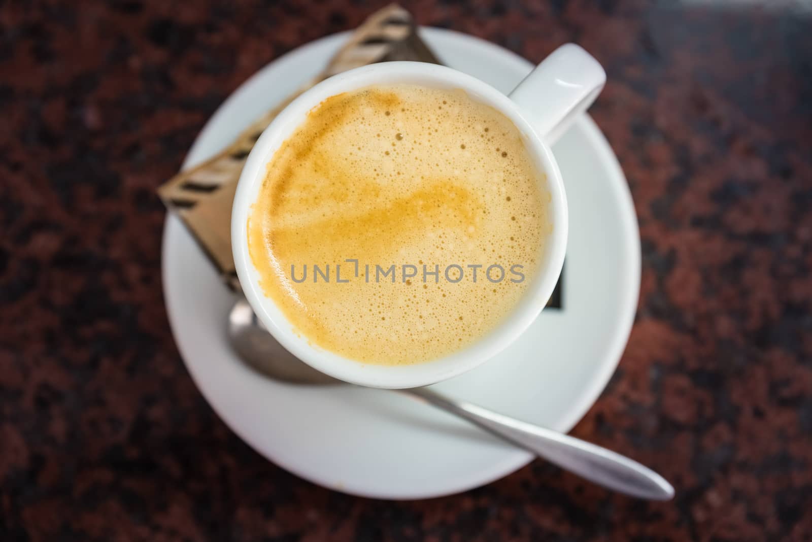 Cappuccino or latte milk coffee in white cup and saucer on a marble table