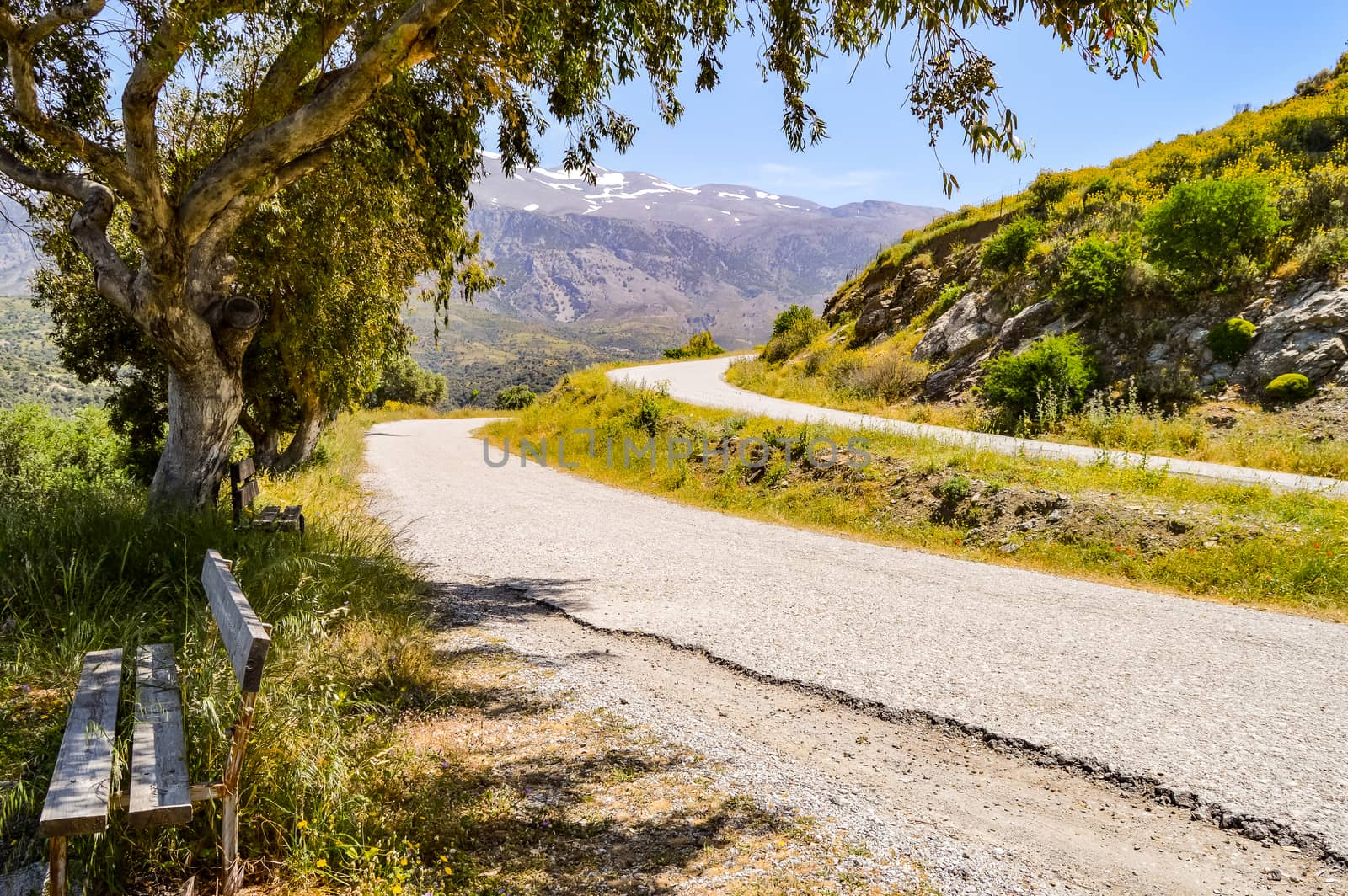 Two parallel mountain roads in Crete with a wooden bench  by Philou1000