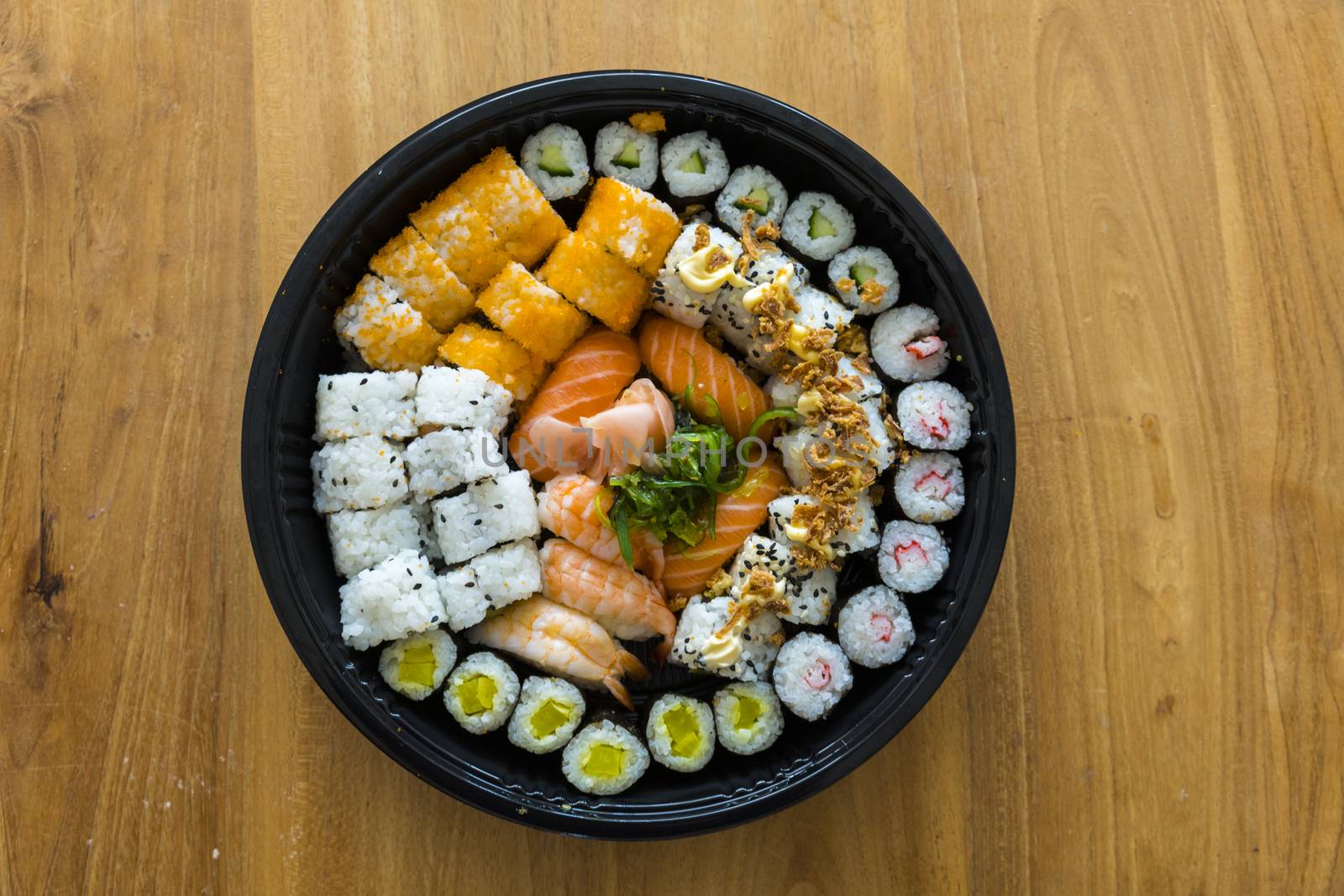 A fresh platter of sushi with rice and fish isolated on wooden table