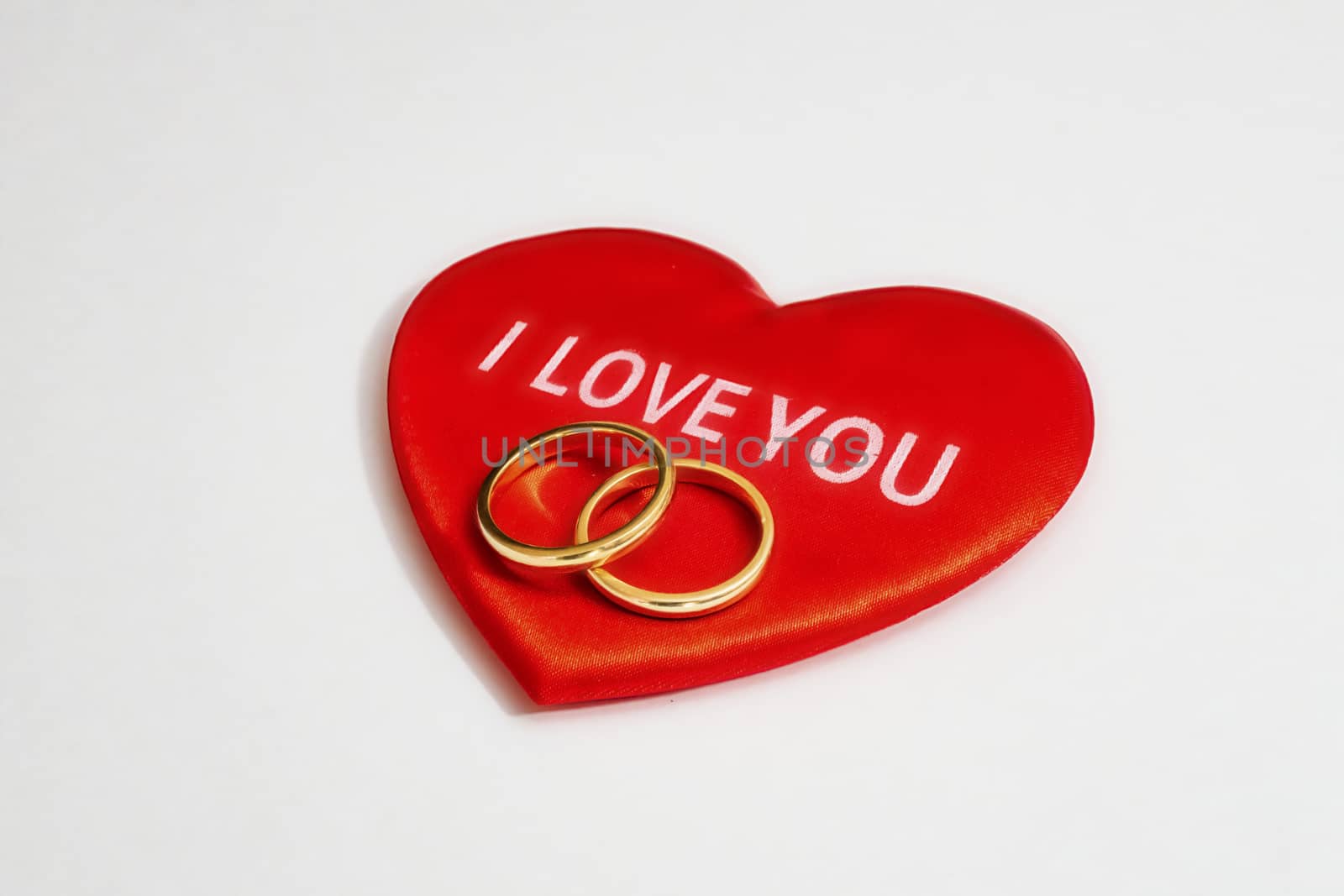 red hearts and wedding rings on a white background