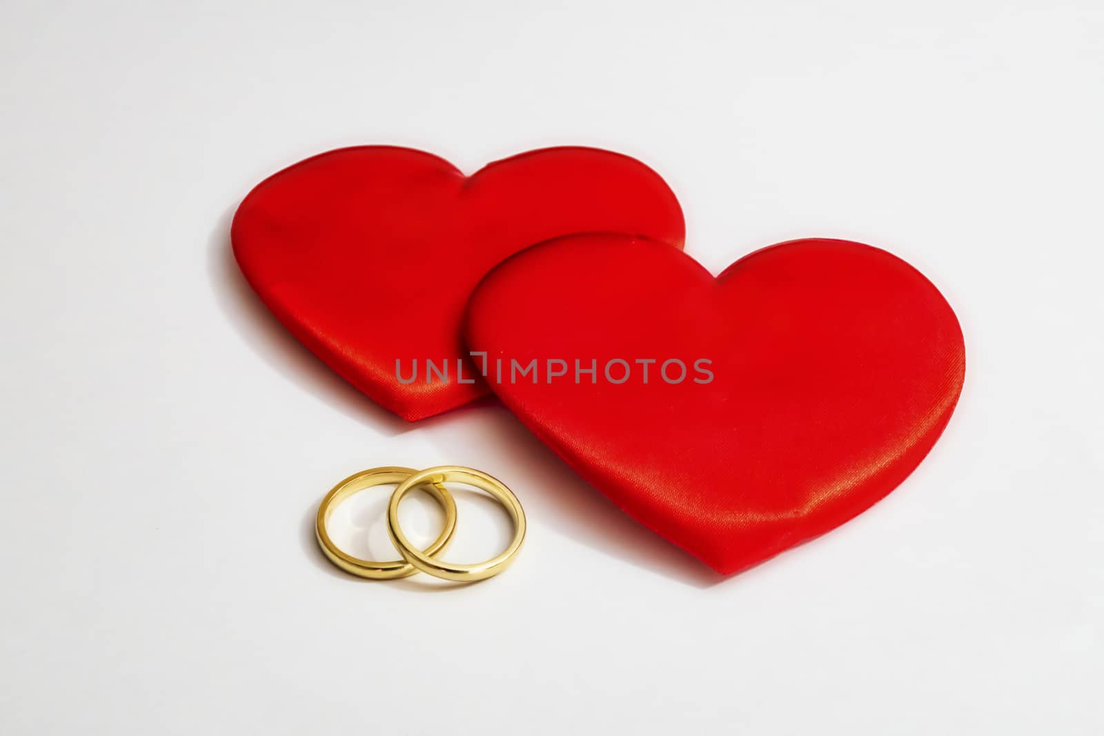 red hearts and wedding rings on a white background